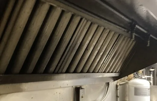 Hood baffle filters dulled with grease along the cooking line before cleaning
