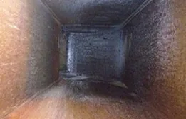 Horizontal exhaust duct interior lined with dark grease before cleaning